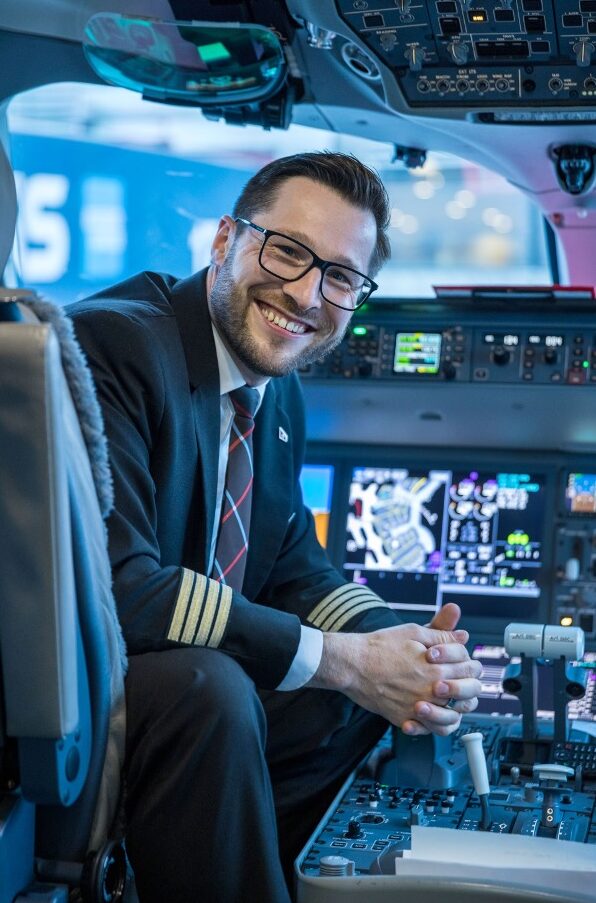 Junger Pilot mit Brille sitzt im Cockpit